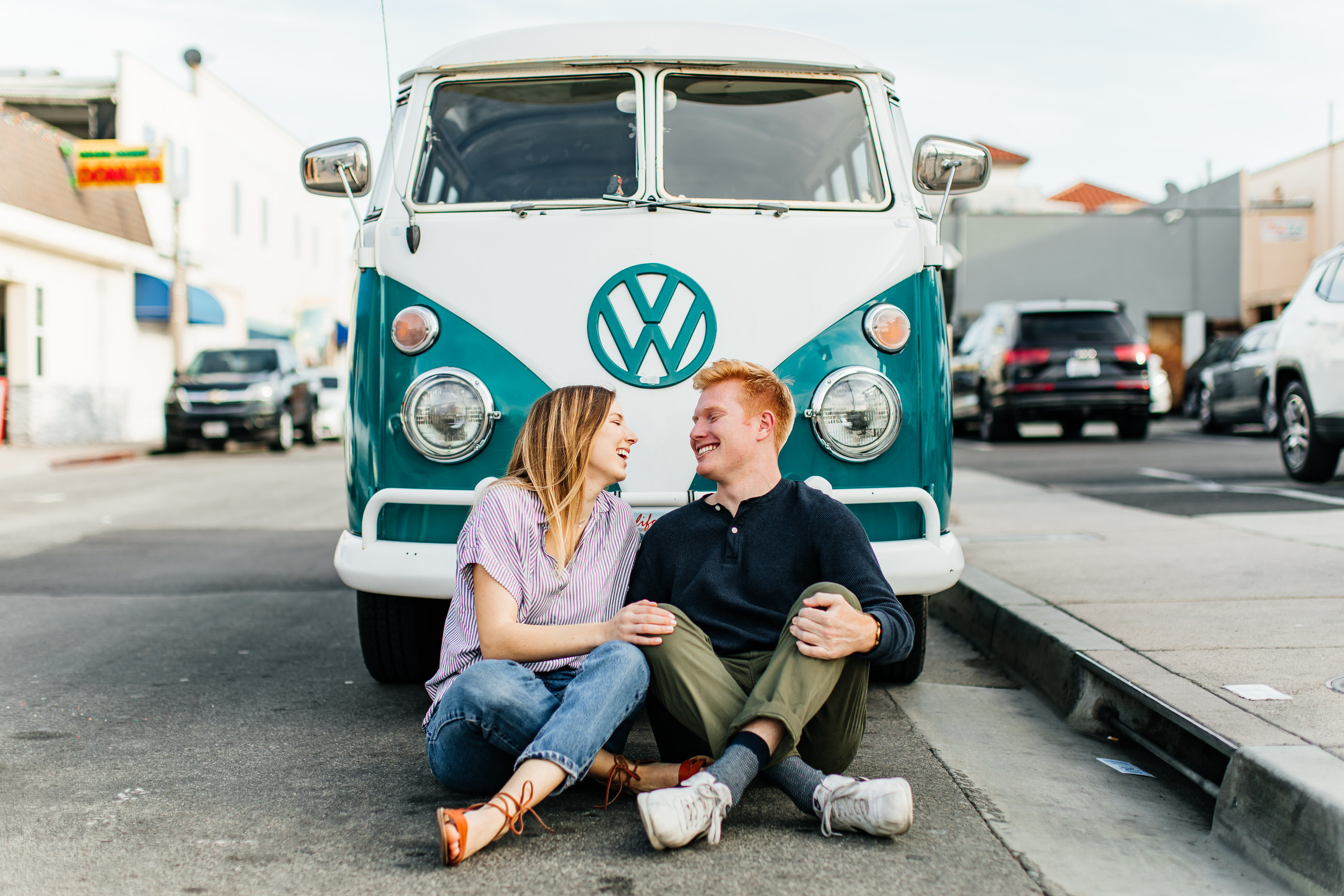 Balboa fun zone engagement photos in Newport Beach couple laughing in front of vintage vw bus