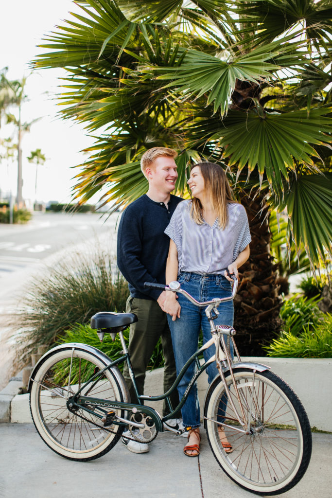 Balboa Fun Zone engagement photos in Newport Beach: Couple riding bikes for engagement pictures 
