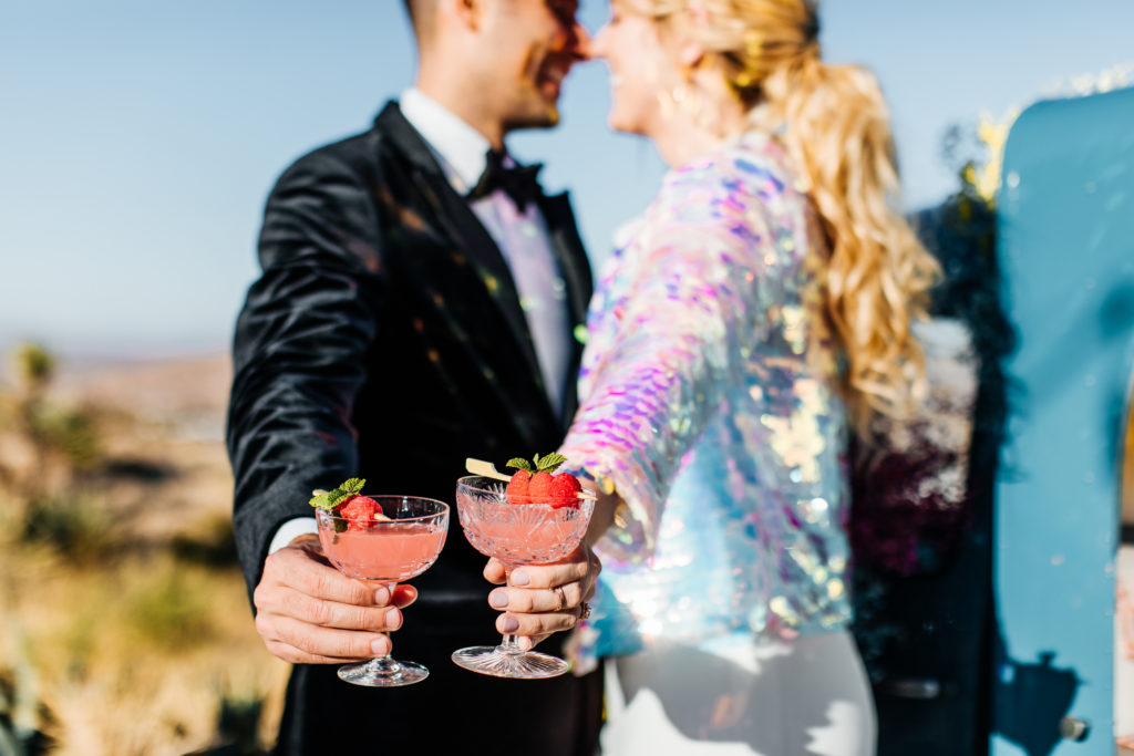 Bride and groom holding colorful cocktails at their wedding