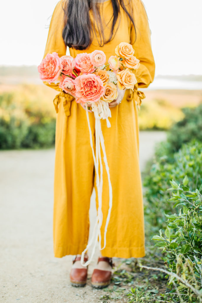 Southern California florist cultivated by faith holds vibrant bridal bouquet with coral and orange color scheme