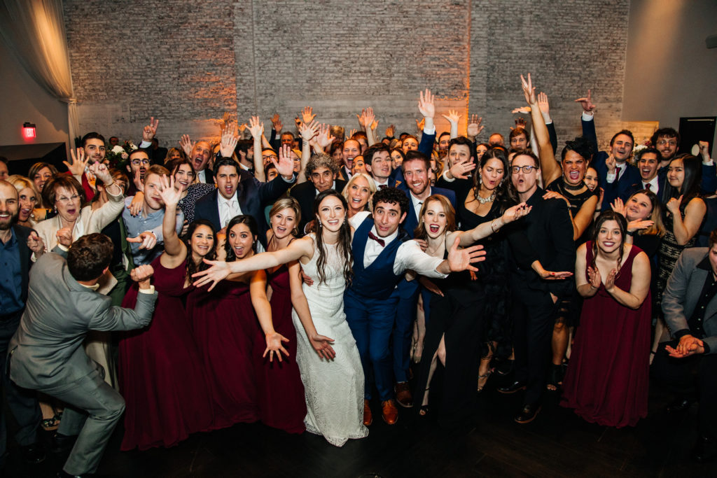 group photo of bride and groom with all their guests on the dance floor