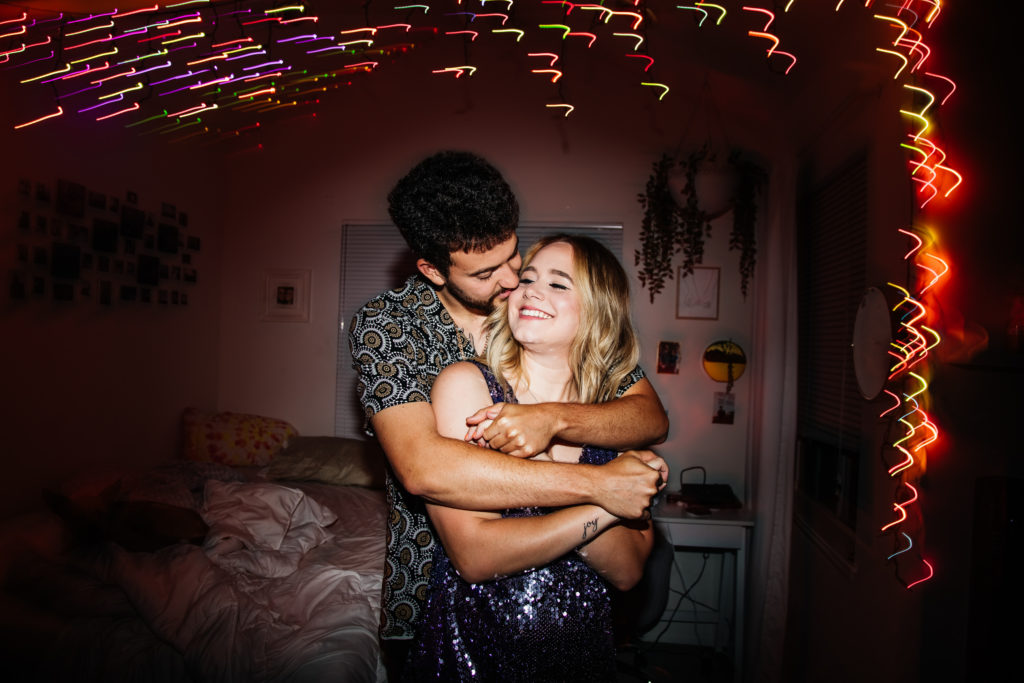 couple hugs and kisses for photo with rainbow light streaks