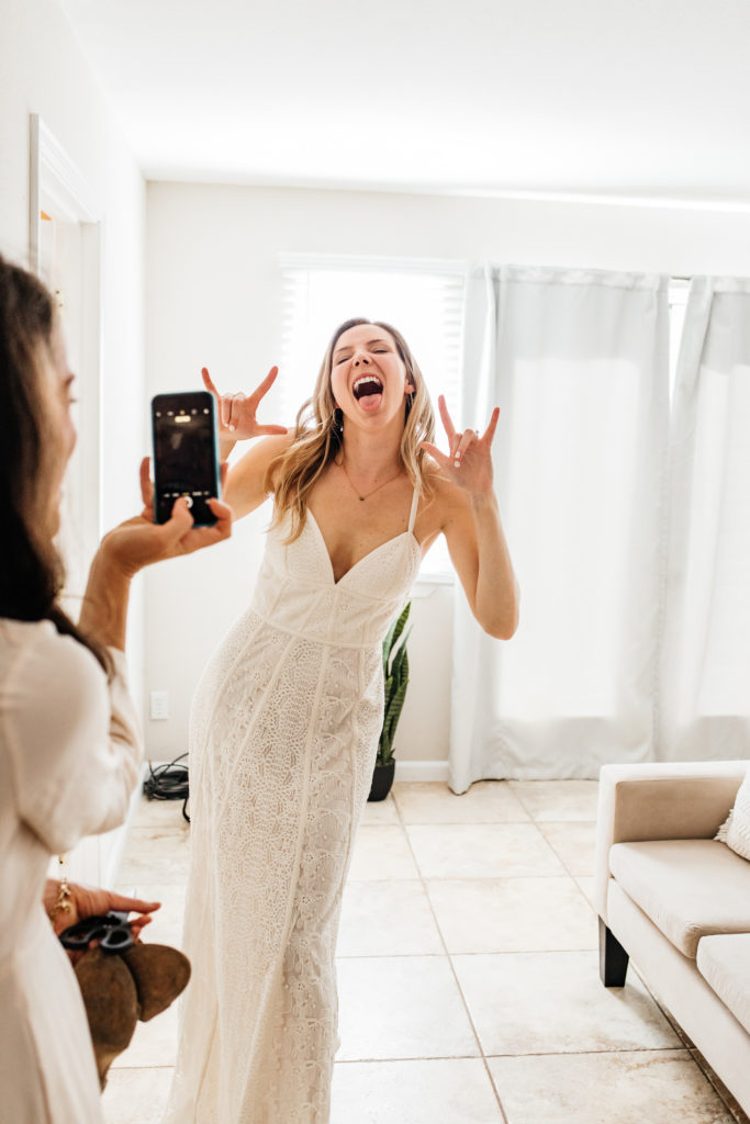 bride poses for a silly rock on photo in her wedding dress