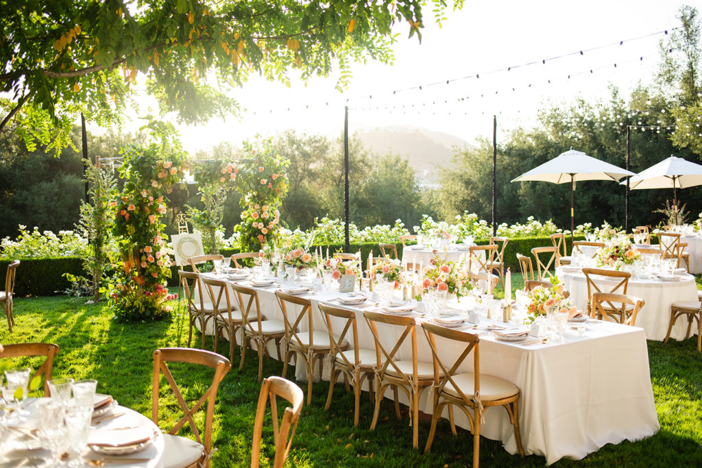 outdoor wedding reception with a long farmhouse style table and colorful flower arrangements