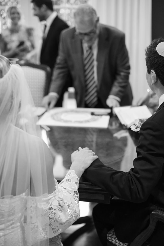 bride and groom hold hands during their ketubah signing
