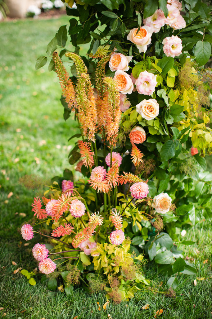 bright pink and orange flower details on the wedding arch