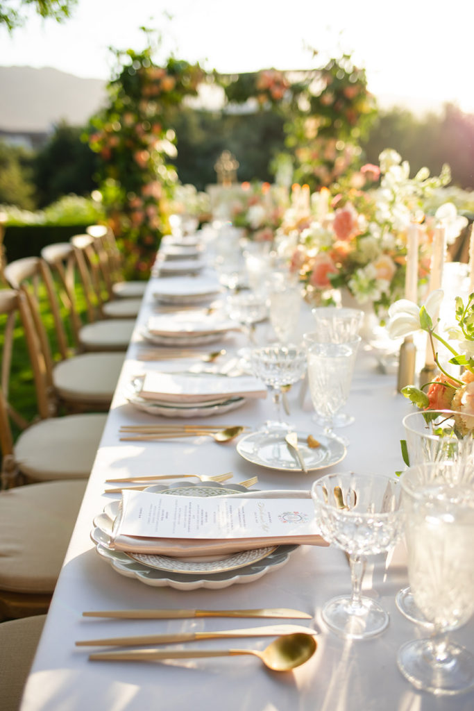 scalloped edged dishes and golden utensils arranged on the table for dinner at the wedding reception