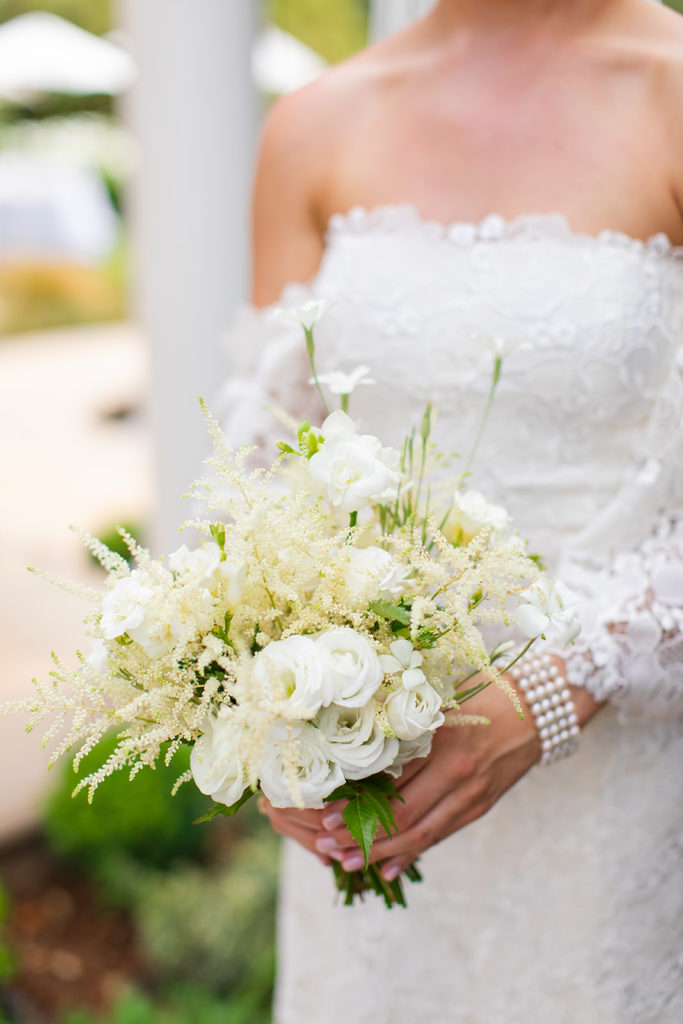 bride holds a bouquet of white roses and queen Anne's lace