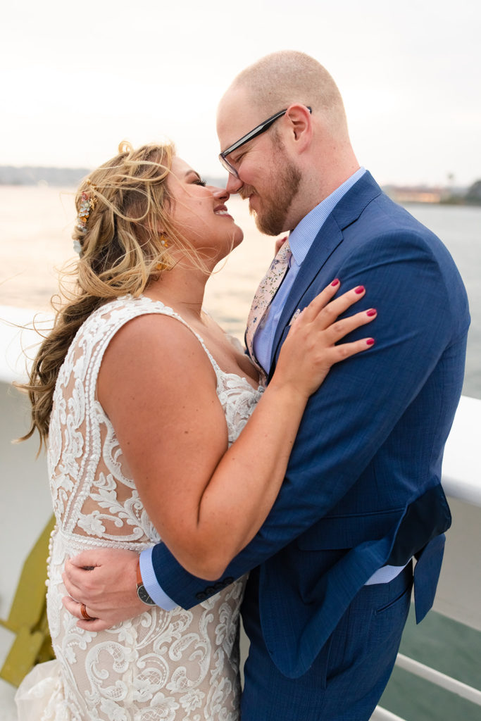 bride and groom kissing at sunset on a boat