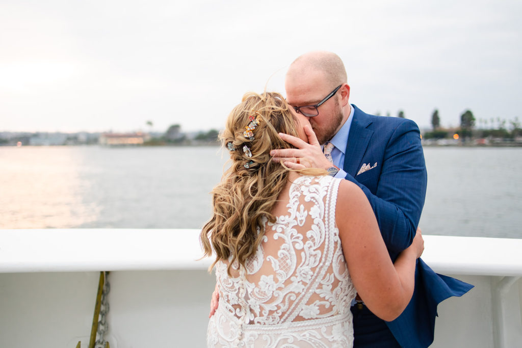 bride and groom kissing on a boat as the sun sets