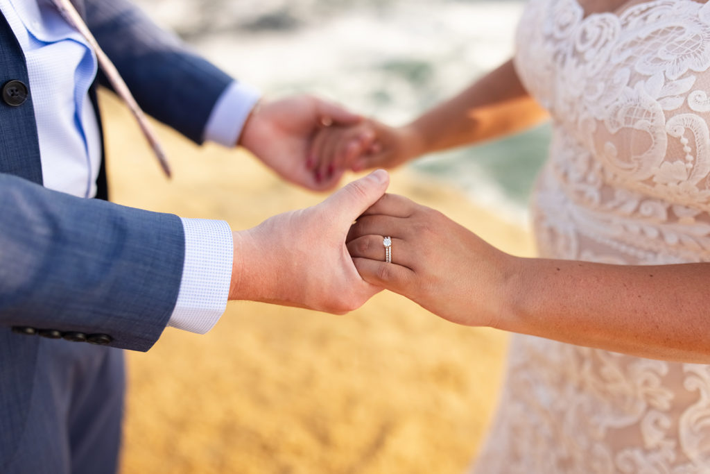 bride and groom holding hands at their wedding on the beach