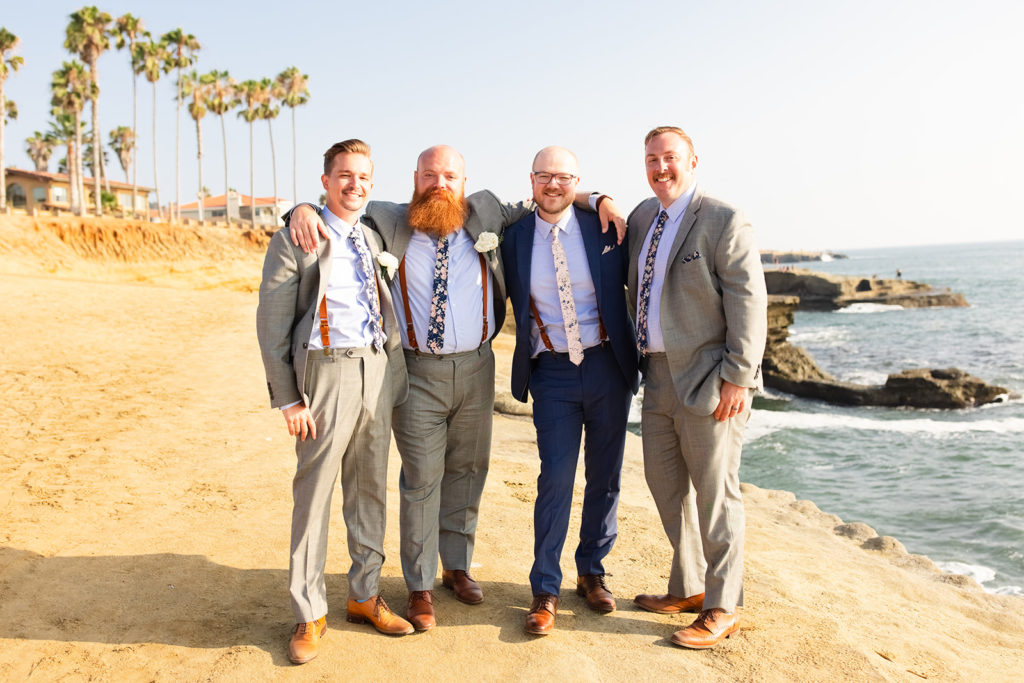 groomsmen smiling together in a group on the beach