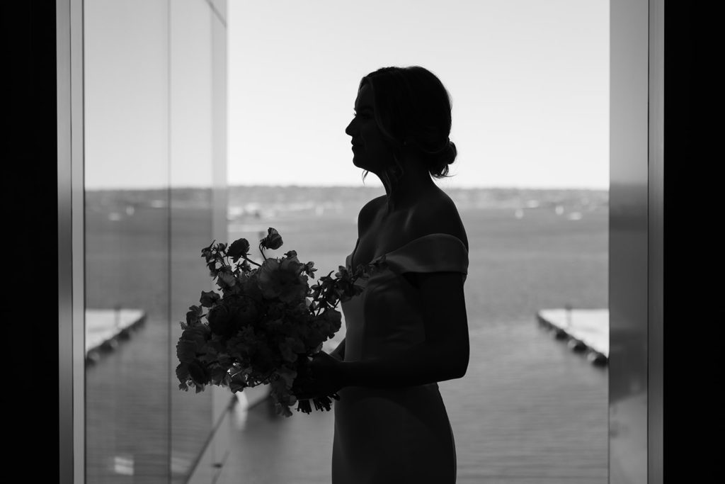black and white profile photo of bride holding her bouquet on the waterfront