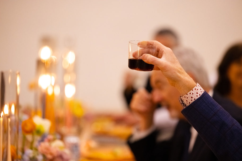 wedding guest lifts a wine glass to cheers after a toast