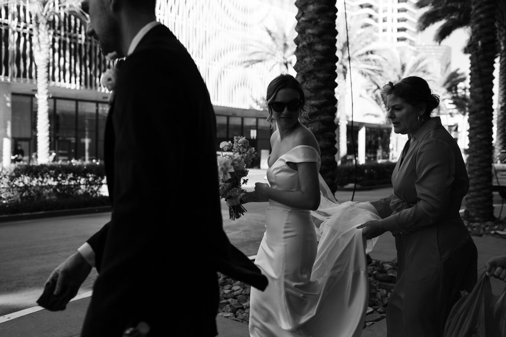 black and white photo of bride and groom walking across the street to their venue