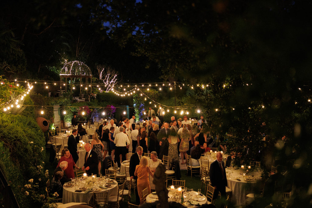 overhead view of outdoor evening wedding reception surrounded by greenery and string lights