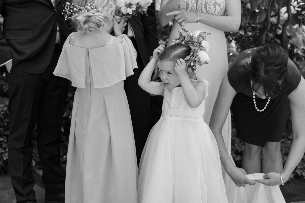 flower girls play with their flowers during candid family pictures