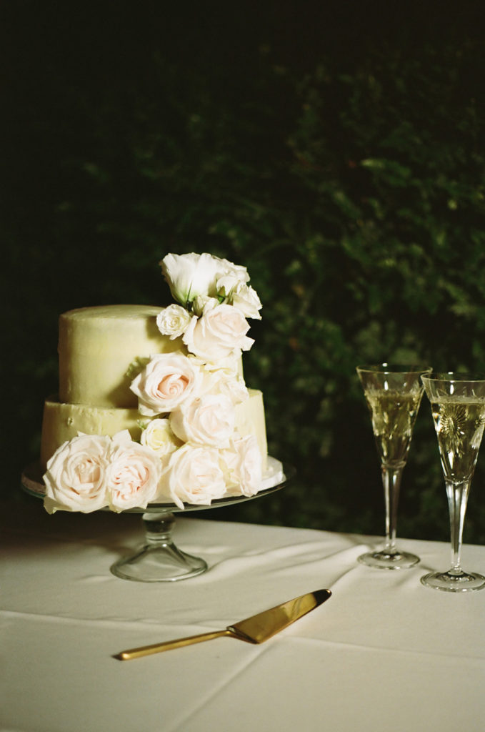 classic white wedding cake with roses and champagne glasses