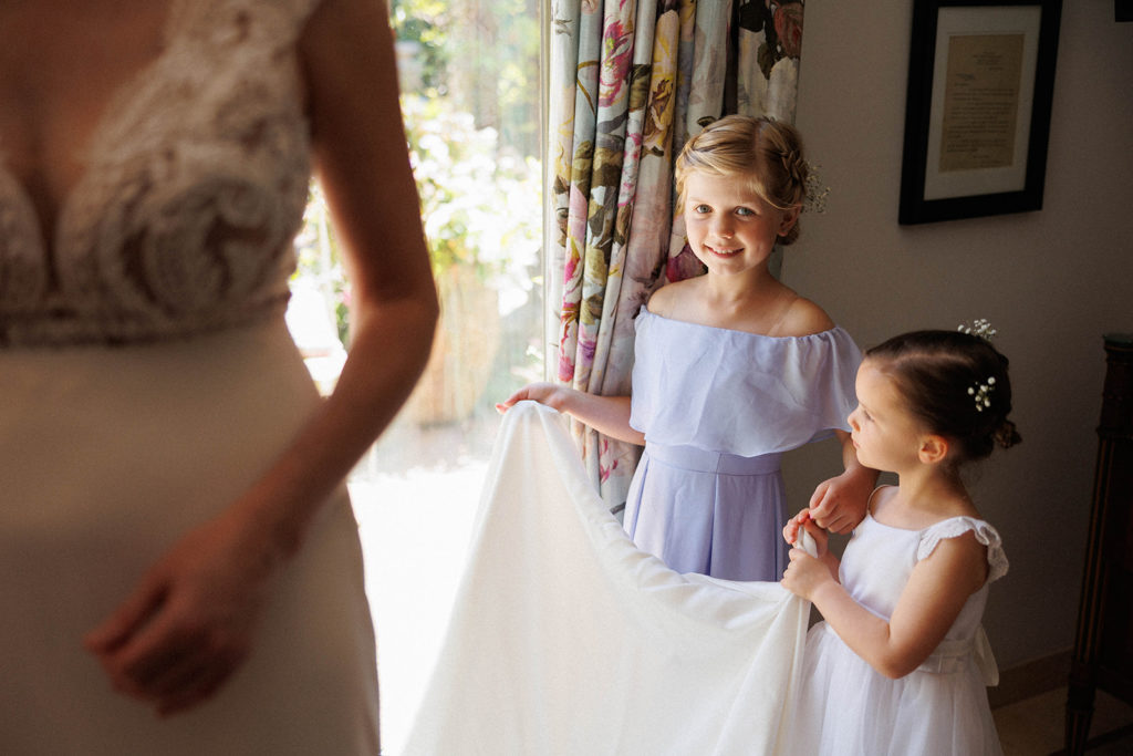flower girls hold the bride's wedding dress during getting ready