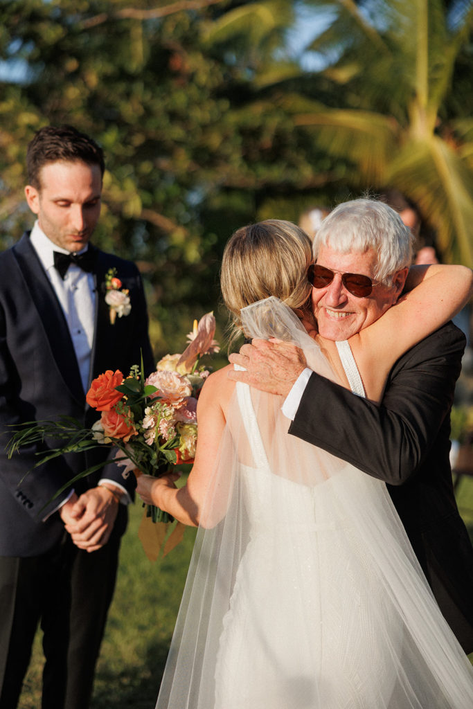 bride's father hugs her after walking her down the aisle