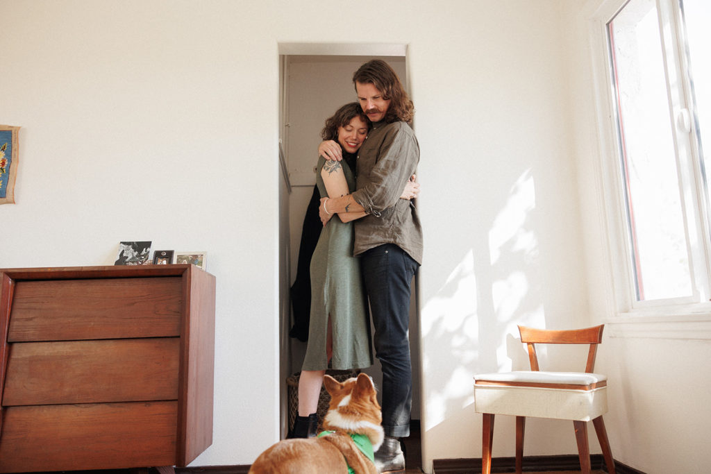couple cuddles in their home with their dog