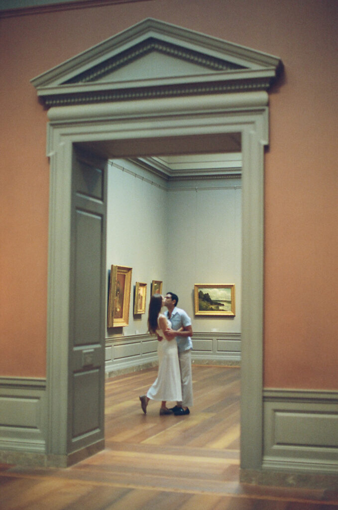 couple kisses romantically in an art gallery