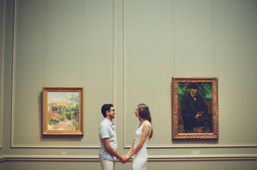 couple holds hands surrounded by impressionist paintings