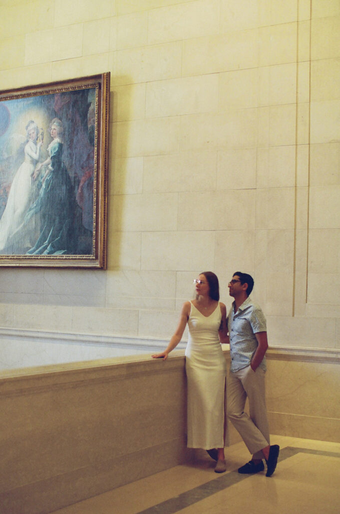 couple pauses in a museum near a classic painting