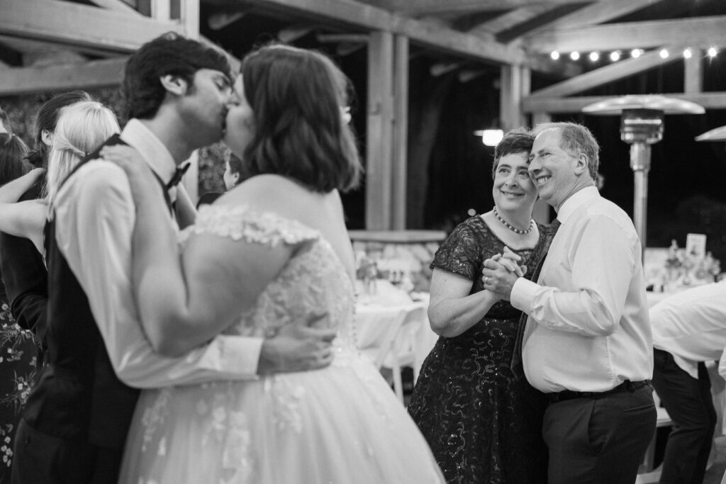 groom's parents smile at the couple on the dance floor