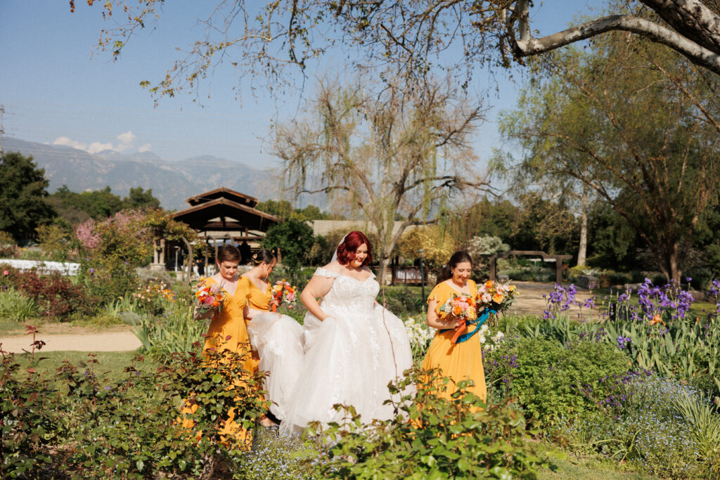 bride and her bridesmaids stroll through a garden together