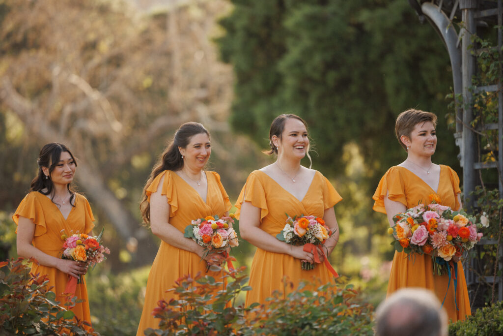 bridesmaids smile and laugh during wedding ceremony