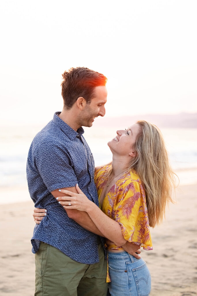 couple hugs after sunset proposal in Santa Monica