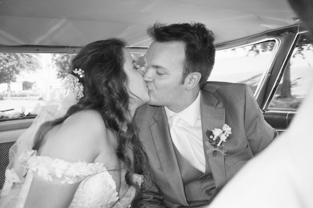 bride and groom kiss inside a classic car on their wedding day 