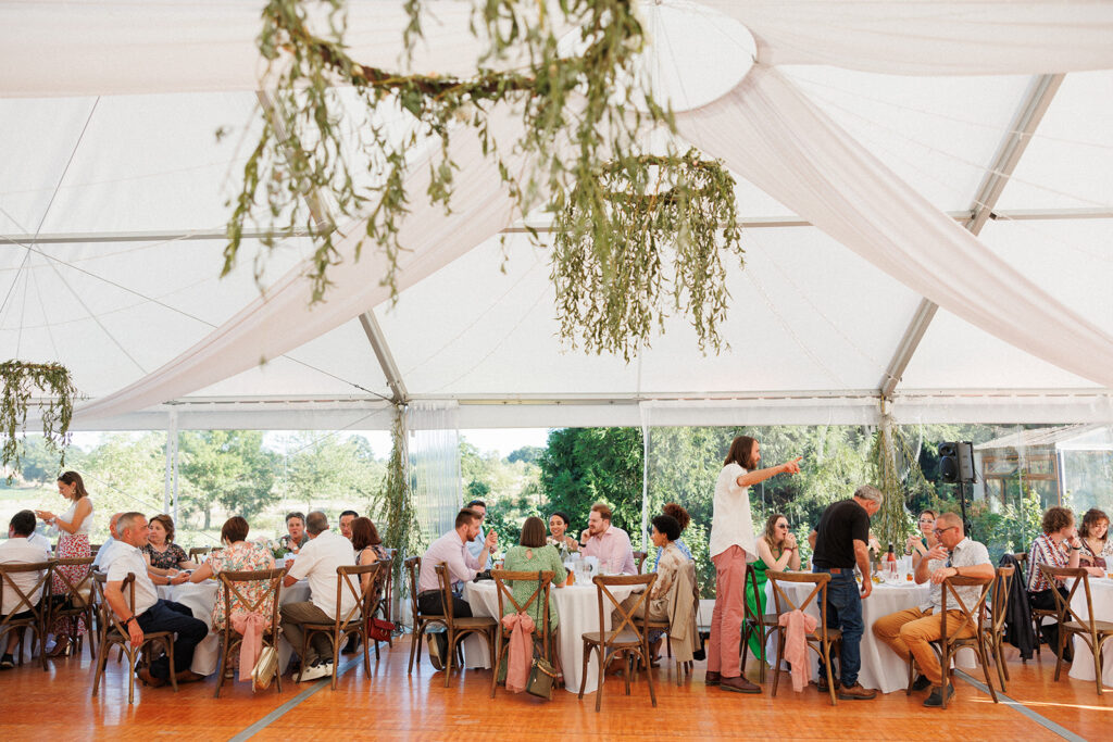wedding guests gather under a tent in the French countryside