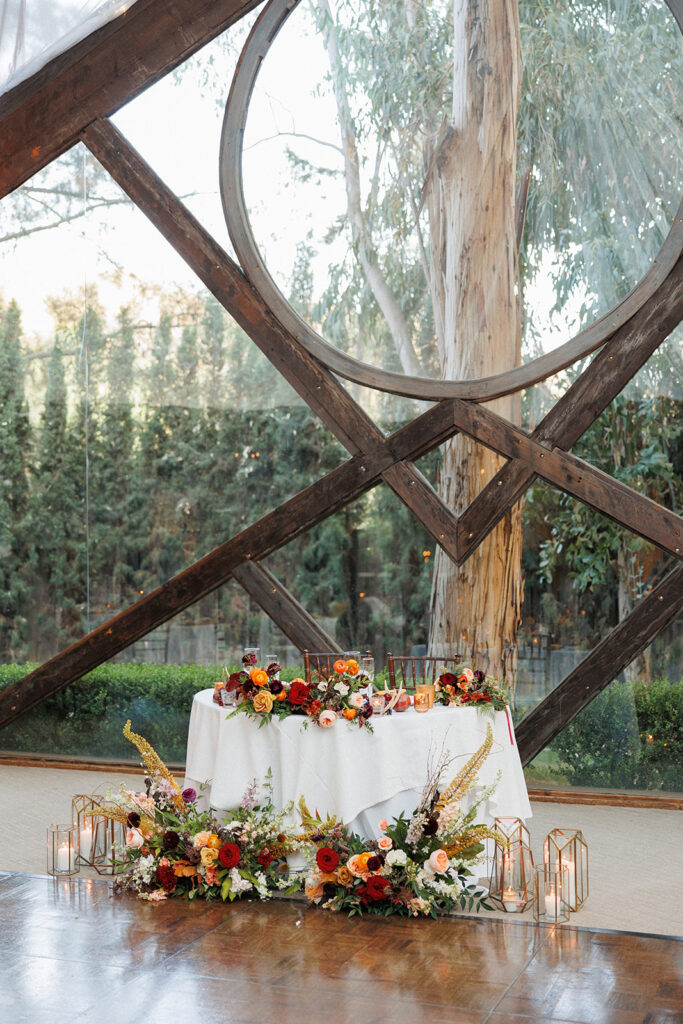 loose jewel-toned flower displays grace the sweetheart table at this Calamigos Ranch wedding in Malibu