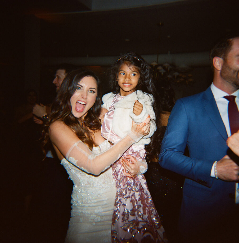 Bride holding a little kid on dance floor 
