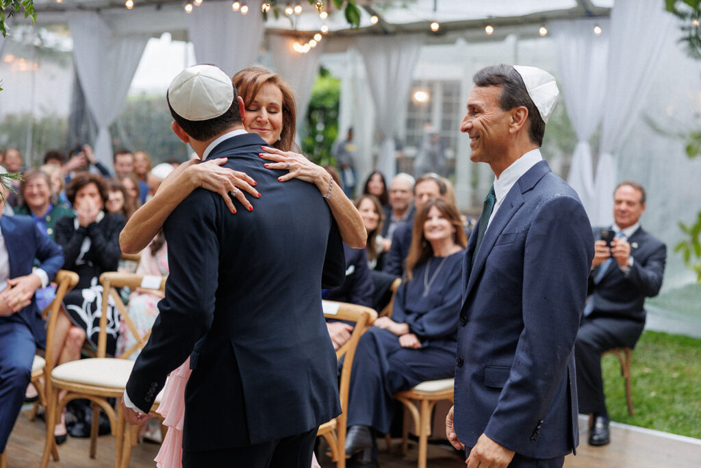 groom embracing parents during wedding ceremony 