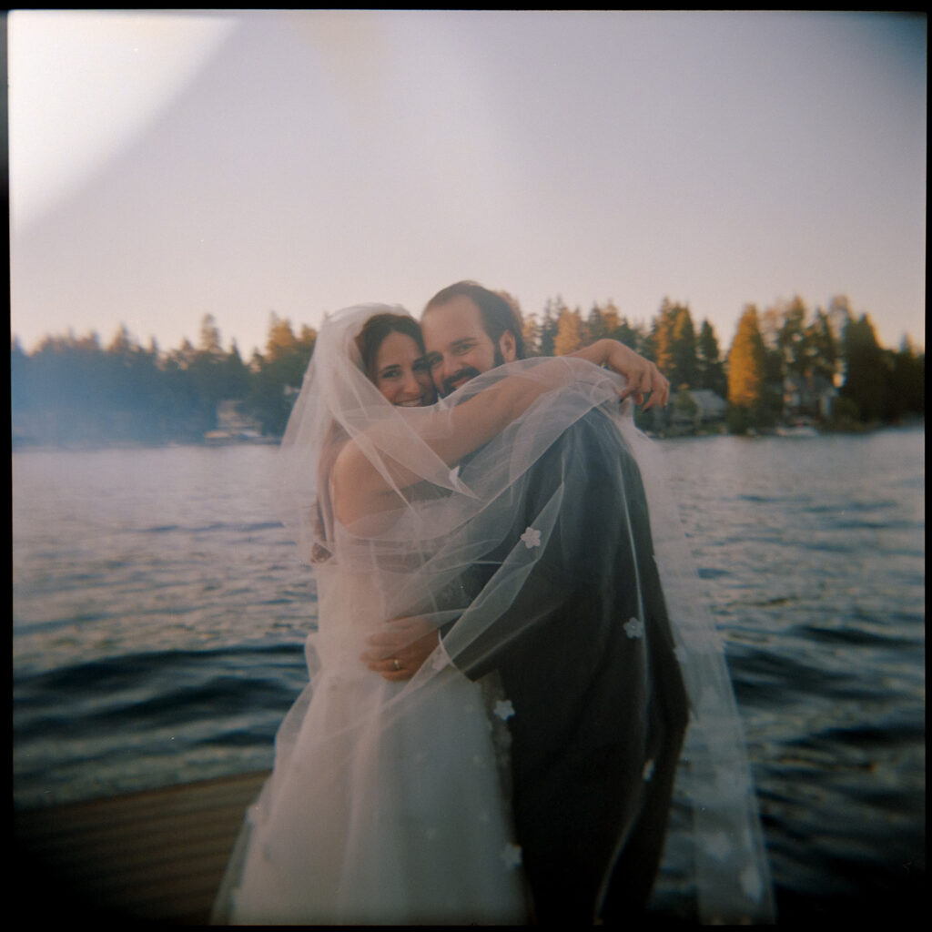 stunning film photo of bride and groom hugging by the lake