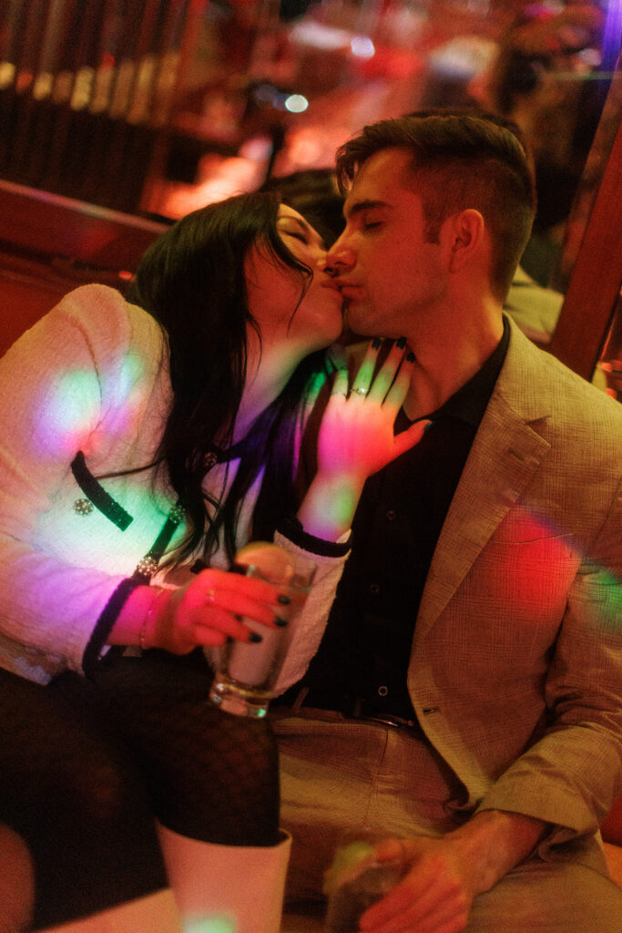 Close-up of the mirrored ceiling filled with disco balls, casting light patterns over the couple as they share a quiet moment in the midst of a vibrant room.
