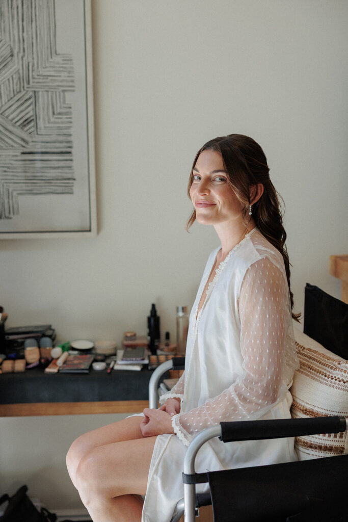 bride smiles while sitting in the makeup chair inside her guest room at Calamigos Ranch