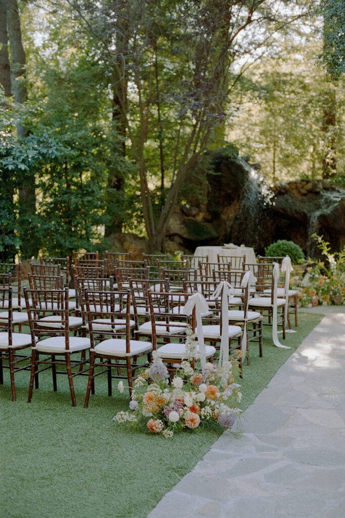 ceremony chairs set up for wedding ceremony at Birchwood Room, decorated with white silk bows and ground floral arrangements 