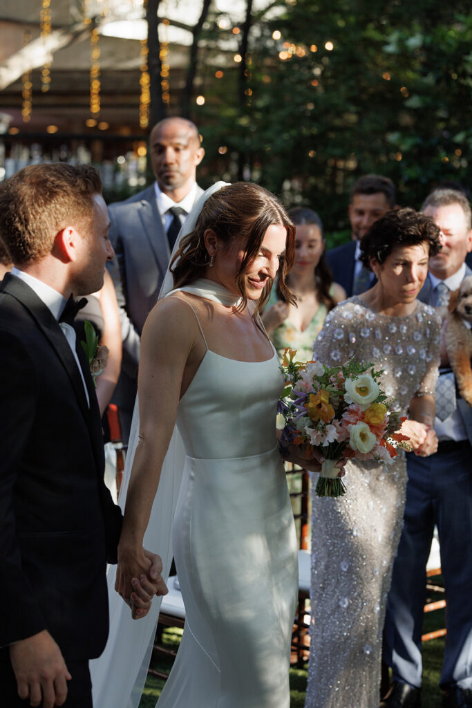 bride and groom hold hands and walk towards the altar together for their wedding ceremony at Birchwood Room