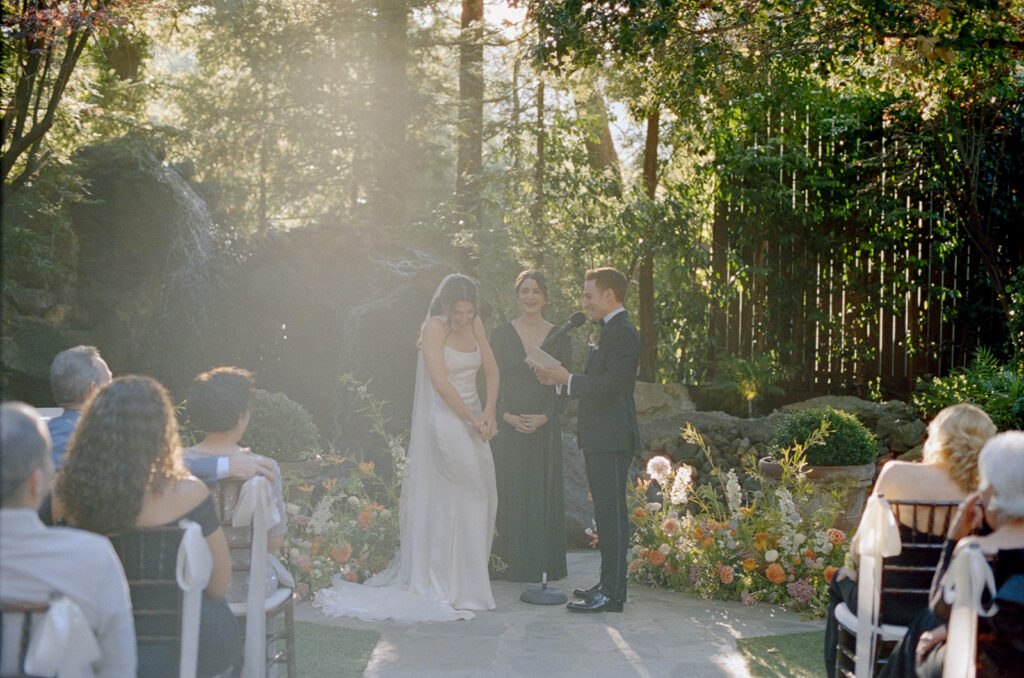 bride laughs as groom reads his vows to her during their wedding ceremony at Birchwood Room
