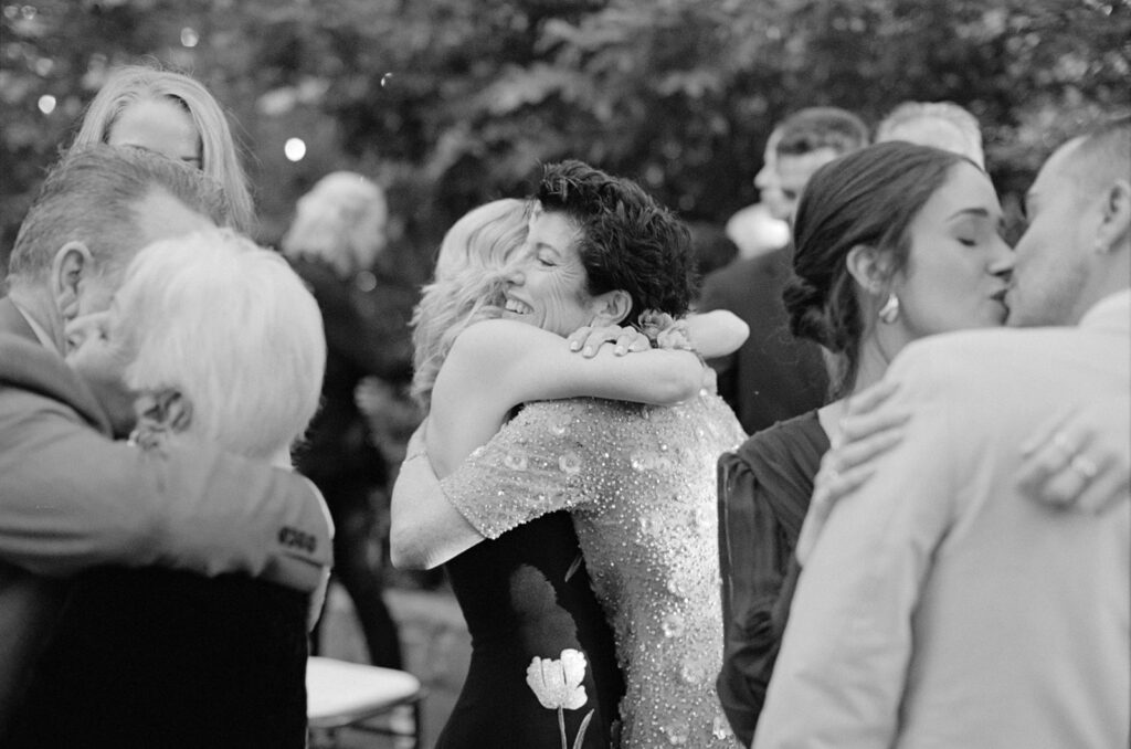 wedding guests embracing in a classic black and white film photo at the end of a Calamigos Ranch wedding ceremony 