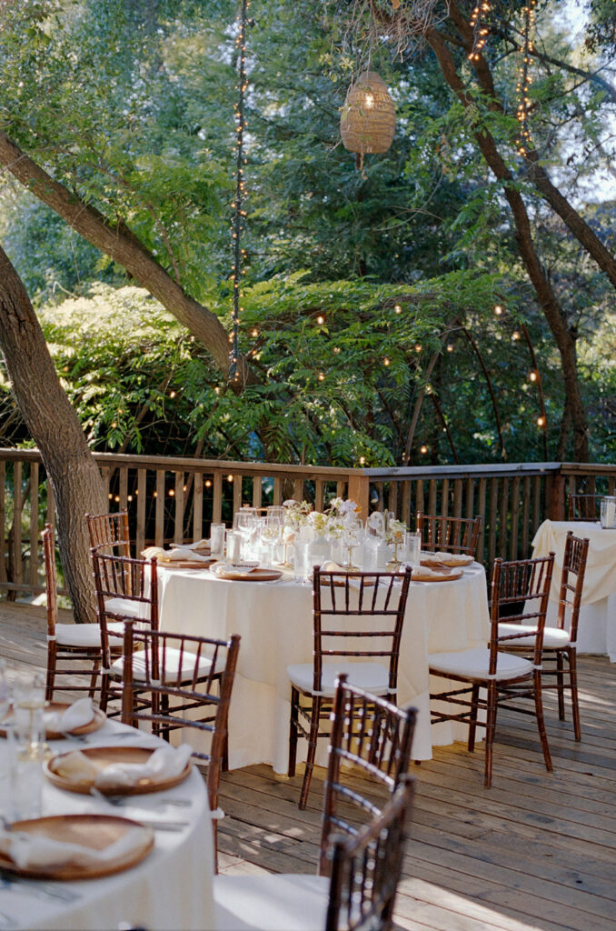 afternoon light highlighting the wedding reception tables decorated with flowers and candles on the wooden deck at Birchwood Room