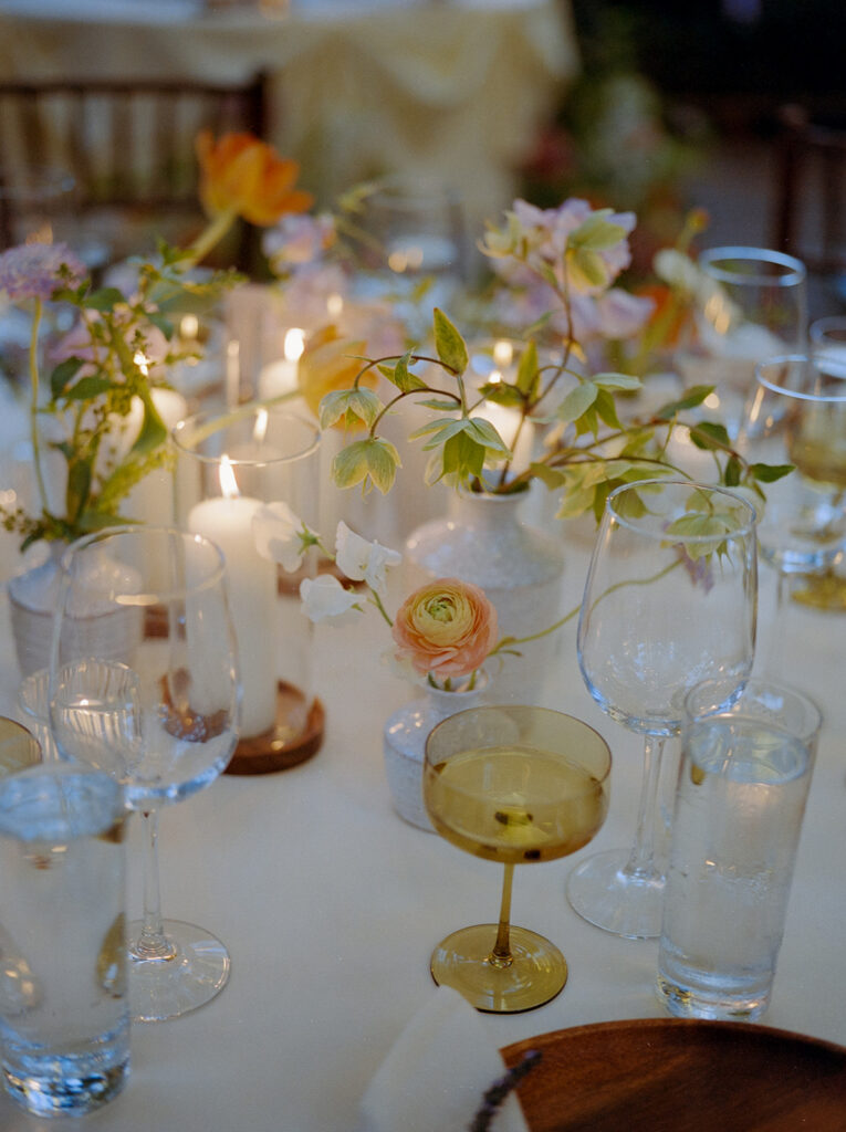close up of wildflower bud vases and candles and glassware on wedding reception tables at Calamigos Ranch in Malibu